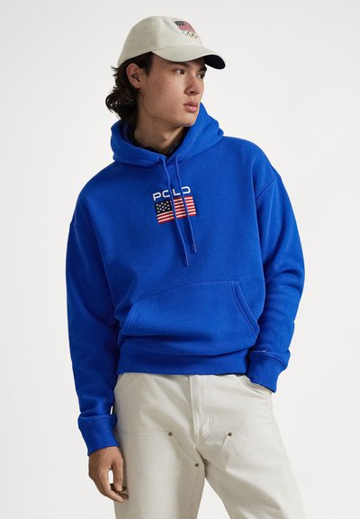 Blå bomulls hettegenser med frontlomme og "Polo"-logo med amerikansk flaggdesign. Beige caps med OL-emblem.