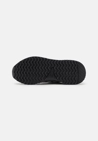 Suola di scarpe in gomma nera con scanalature texturizzate per una migliore aderenza e un dettaglio con logo al centro, progettata per durabilità e grip.