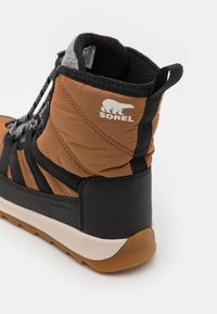 Vanntett brun og svart støvel med polstret design, teksturert lær, justerbare snørebånd og en hvit logo på siden.