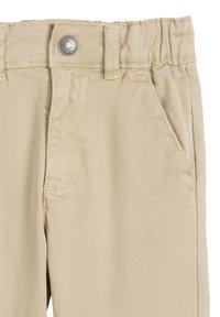 Beżowe spodnie z bawełny z domieszką elastanu, z elastycznym paskiem w talii, przednią kieszenią i metalowym zapięciem. Gładka tekstura z delikatnym skośnym splotem.