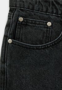 Crni traper džep s detaljima od metalnih zakovica, teksturirane tkanine i vidljivog šivanja. Džep ima klasičan oblik i dizajn.