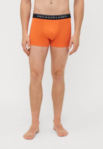 Oranžinės boxer tipo apatinės kelnaitės, pagamintos iš medvilnės mišinio, su juodu elastingu juosmeniu, ant kurio yra "POLO RALPH LAUREN" logotipas. Prigludusi forma, iki šlaunų vidurio.