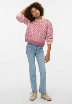 Suéter rosa con estampado, de forma cuadrada y puños acanalados, combinado con vaqueros de pierna recta azul claro y zapatillas beige. Fondo liso.