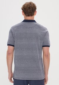 Polo à manches courtes avec un col marine, tissu gris à rayures horizontales texturées et un motif subtil, design léger.