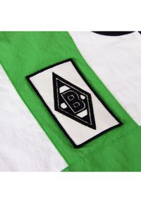 Groen en witte stof met een textuurpatch waarop een zwart-wit diamanten logo staat, omrand door zwarte stiksel.