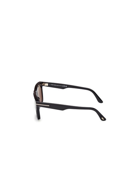 Black sunglasses with brown lenses, featuring a thick frame and sleek, angled temples. Gold accents on the outer sides add detail.