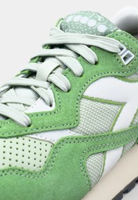 Green suede and mesh sneaker with white accents, textured panels, and a padded collar. Features lace closure and perforated detailing.