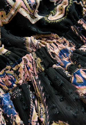 Sort stof med pink, blå og gule paisley-mønstre; har teksturerede, samlede sektioner og flossede kanter for ekstra detaljer.