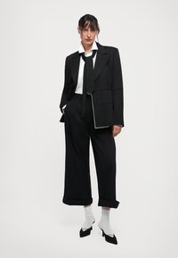 Musthave mustriga mustri, mis on koos valgete aktsentidega, paaritud sobivate laia jala pükstega. Viimistletud valge särk ja must lips. Mustad teravad kontsad.