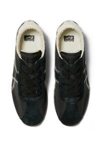Zapatillas deportivas de ante negro y tela con acentos texturizados, cordones redondos y un interior acolchado. Presentan patrones de costura visibles.