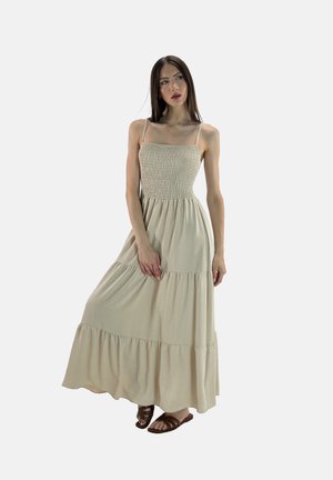 Maxikjole i lys beige, med en smocket bodice og lagdelt skirt. Tynde spaghetti-stropper og blød tekstur. Begyndes med brune sandaler.