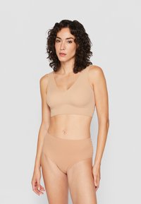 Beige seamless bralette met een V-hals en brede banden, gecombineerd met hoge taille beige onderbroek, beide van een gladde, elastische stof.