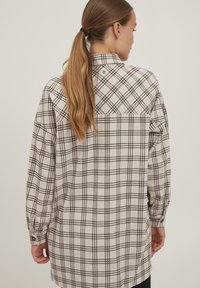 Karierte Hemd mit einem beigefarbenen und braunen Muster, langen Ärmeln, Knopfschluss am Kragen und einer lockeren Passform mit einem Rückenteil im Yoke-Stil.