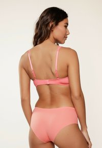 Roze bh en bikinibroekje set met een gladde textuur. De bralette heeft verstelbare bandjes. De stof is zacht en aansluitend.