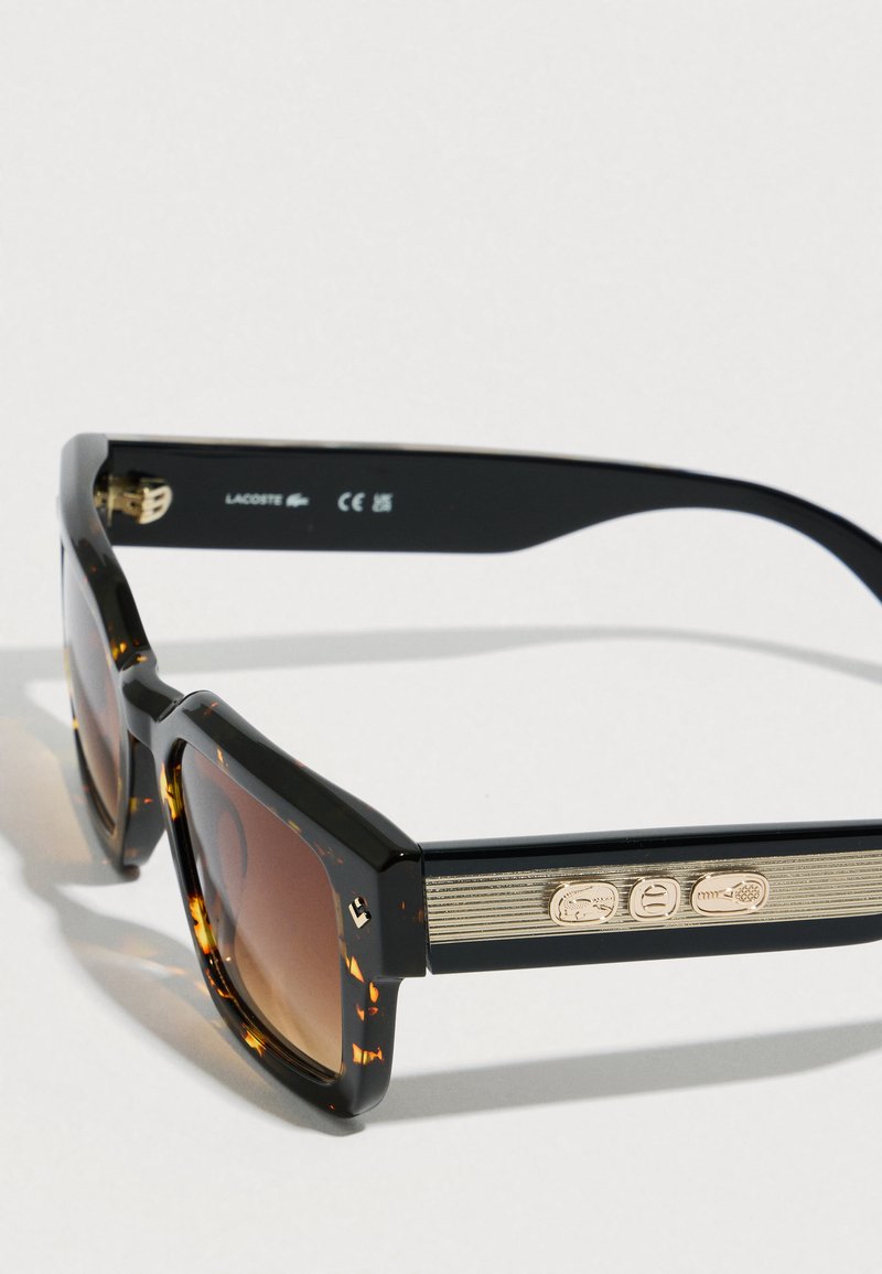 Rektangulære solbriller med skildpaddeprint, gradientbrune linser og gyldne dekorative logoer på stængerne.