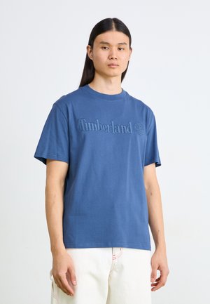 Blå bomulds t-shirt med "Timberland" logoet præget på brystet, med korte ærmer og et klassisk rundhalset design.