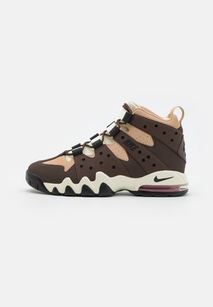 Chaussure de basketball montante Nike en marron et beige avec des accents noirs, semelle intermédiaire en zigzag, talon avec coussinet d'air et languette à l'arrière.