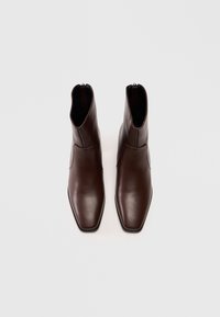 Stivali alla caviglia in pelle marrone con punta quadrata, design elegante, dettagli di cucitura discreti e chiusura con zip sul retro.