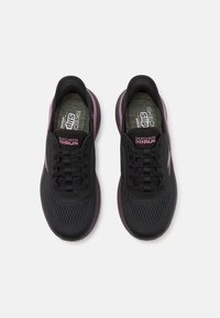 Black athletic shoes with a mesh upper, lace-up design, and purple accents. Features a cushioned insole and textured sole.