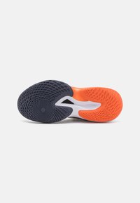 Schoenzool met een gestructureerd zwart rubberen patroon, oranje accent en een witte middenzool met een uitsnijdontwerp voor flexibiliteit.