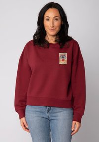Sweatshirt bordeaux  à la coupe décontractée, avec un motif imprimé sur le devant. Tissu doux, manches larges et bord-côte en détail.