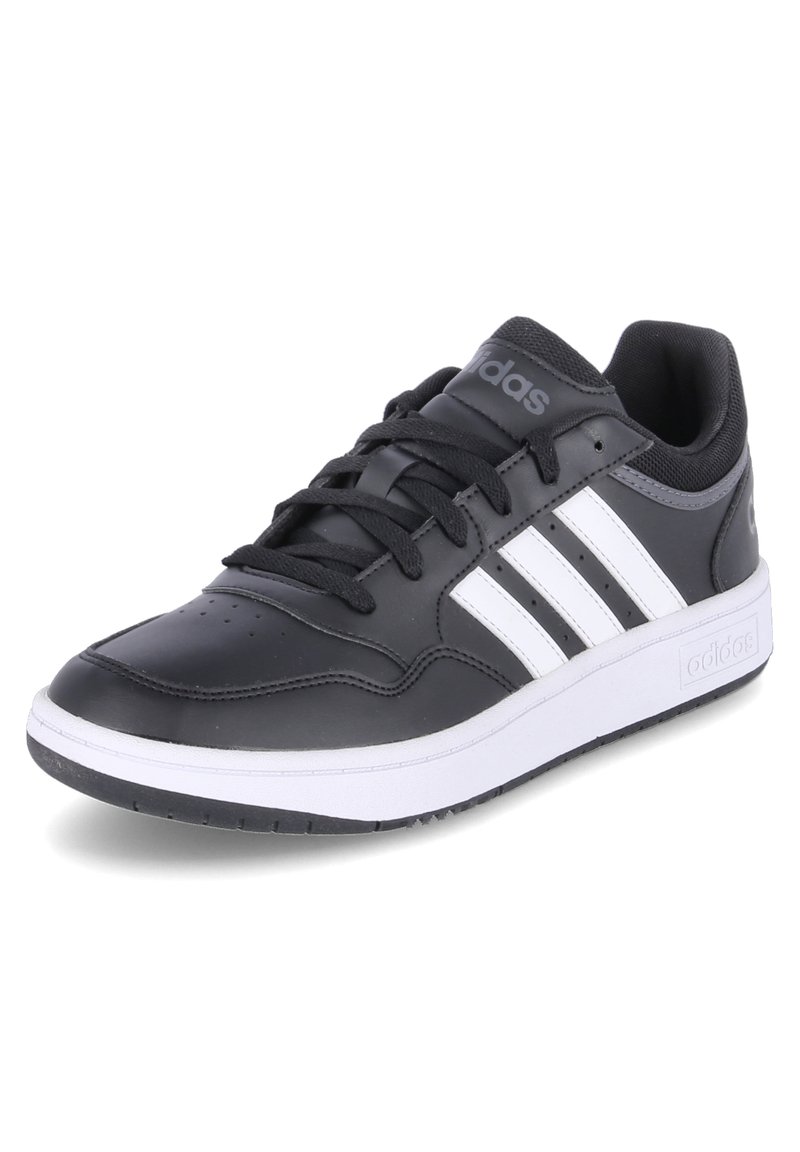 Scarpa sportiva nera in materiale sintetico con strisce bianche, punta rotonda, suola piatta in gomma e lacci in alto. Presenta un collo e una linguetta imbottiti per maggiore comfort.