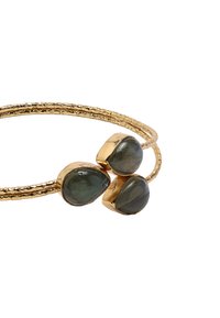 Bransoletka w odcieniu złota z trzema owalnymi zielonymi kamieniami osadzonymi w fakturowanej obręczy o podwójnej skręconej konstrukcji. Gładka i błyszcząca powierzchnia kamieni.