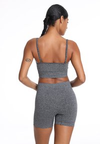 Szary sportowy crop top na cienkich ramiączkach w połączeniu z szortami o wysokim stanie w tym samym odcieniu, oba z miękkiego, strukturalnego materiału i bezszwowym wykończeniem.