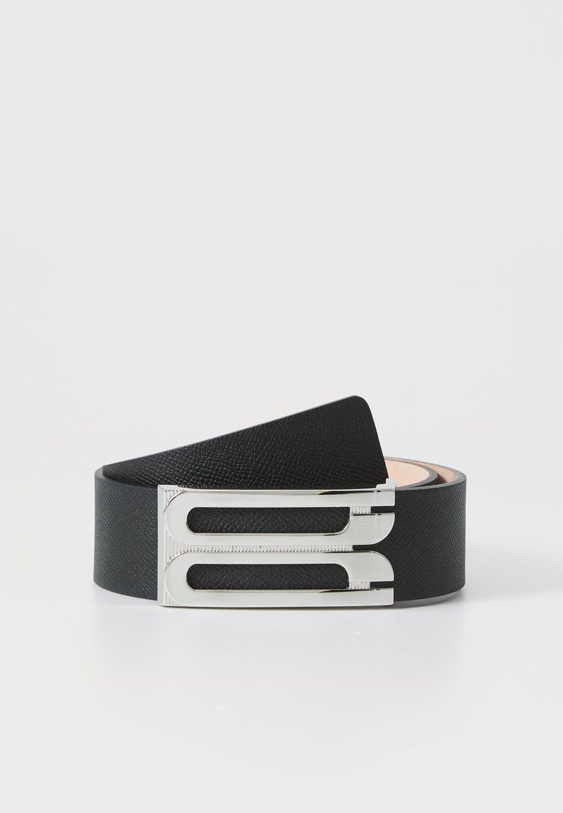 Black leather belt with a textured finish, featuring a silver metallic buckle with an open design and engraved detailing.