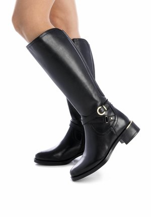Bottes noires en cuir jusqu'au genou avec une texture lisse, bout rond, petit talon carré et accents en or sur la boucle et la sangle.