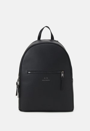 Mochila negra de piel sintética con forma arqueada, que cuenta con un bolsillo con cremallera en el frente, una asa de transporte y un logotipo de marca en la parte delantera.