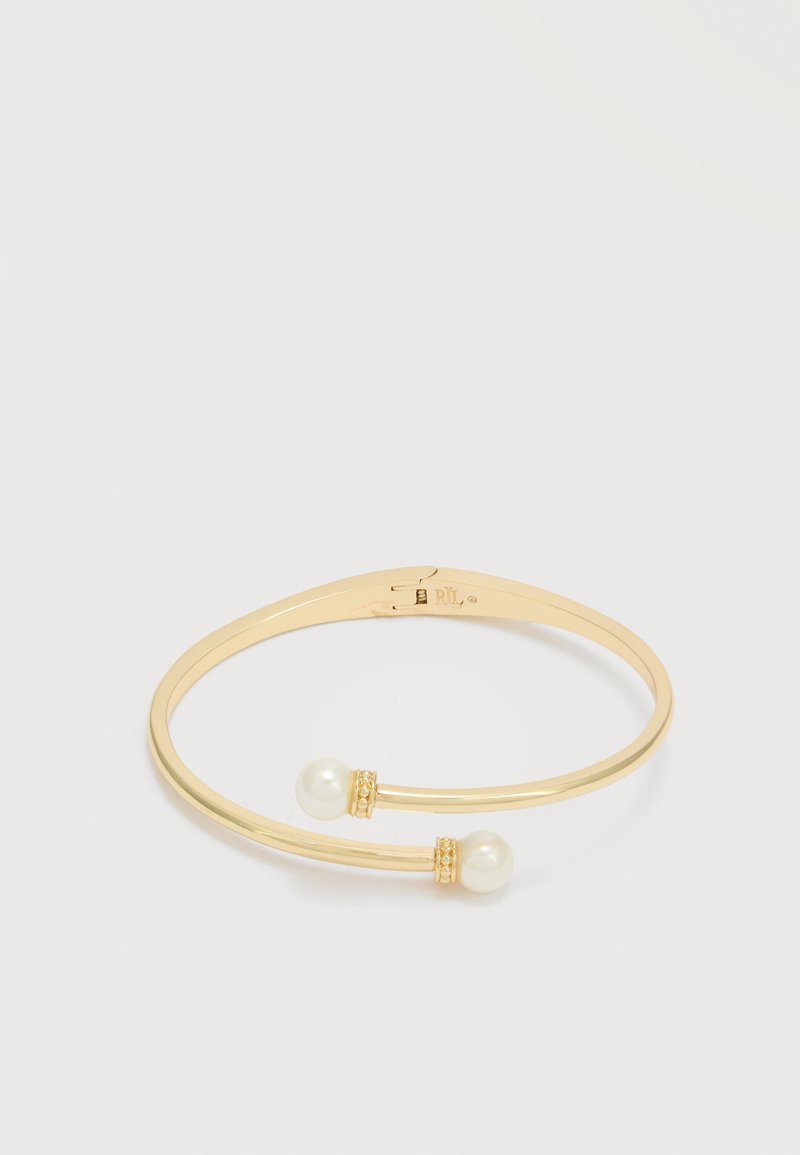 Åben bangle-armbånd i guldfarve med to hvide perler, hver accentueret med små dekorative bånd, på en ensartet hvid baggrund.