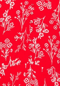 Tejido rojo con patrón floral blanco, que presenta varias flores y hojas. Los botones en el frente realzan el diseño.