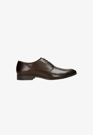 Brown leather dress shoe with a rounded toe, smooth texture, six lace eyelets, and a low heel. Minimalist design with subtle stitching.