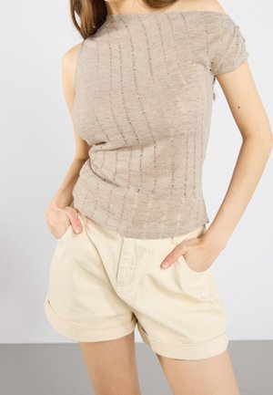 Beige off-shoulder top med teksturerede striber, parret med lysfarvede shorts med manchetter og sidelommer. Begge beklædningsdele er lette.