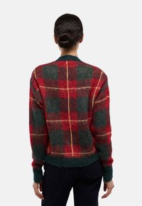 Pull en laine à carreaux rouges et verts avec une texture duveteuse, doté d'un ourlet côtelé, de poignets côtelés, et d'un col rond classique.