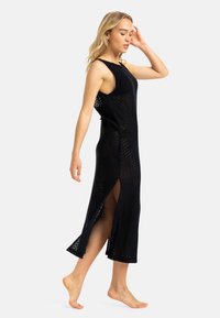 Vestido maxi de punto negro con un patrón de chevrons, diseño sin mangas, aberturas laterales para mayor libertad de movimiento y un corte relajado.