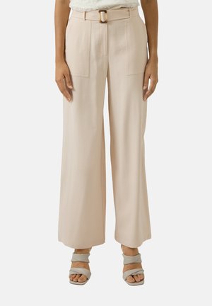 Pantalon beige à jambes larges avec poches plaquées à l'avant et une boucle de ceinture rectangulaire, assorti à des sandales à lanières beige clair.