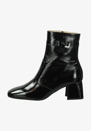 Black ankle boot with a shiny patent finish, pointed toe, block heel, and a silver logo accent on the side. Smooth texture and sleek design.