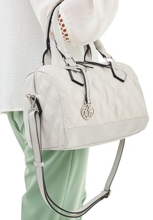 Quilted white handbag with black accents, two short handles, and a detachable shoulder strap. Features a circular logo charm.