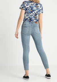 Jeans skinny de denim en un azul claro con una textura suave, combinados con una camiseta de color azul marino con un estampado de olas y un corte holgado.