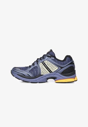 Zapatilla deportiva masculina en azul y negro con paneles de malla, marca Arch-Lock, suela acolchada y detalle amarillo en el talón, vista lateral.