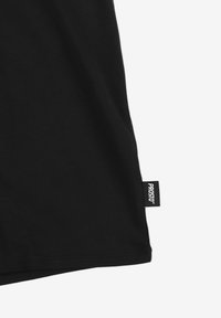 Czarna koszulka z miękkiej bawełny, z prostym dołem i małą metką "PROSTO" z boku. Gładka tekstura bez wzorów.