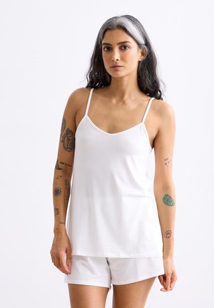 Weißes Trägershirt mit Spaghettiträgern, aus glattem Stoff und lockerem Schnitt, kombiniert mit passenden weißen Shorts. Minimalistisches Design.