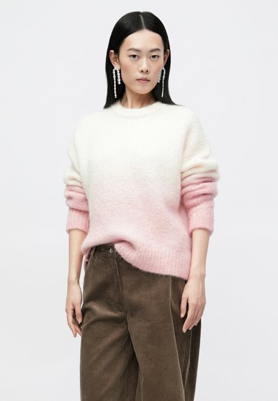 Striktrøje med en gradient fra hvid til lyserød, med en afslappet pasform og drop-skulderdesign. Matchet med brune fløjlsbukser.