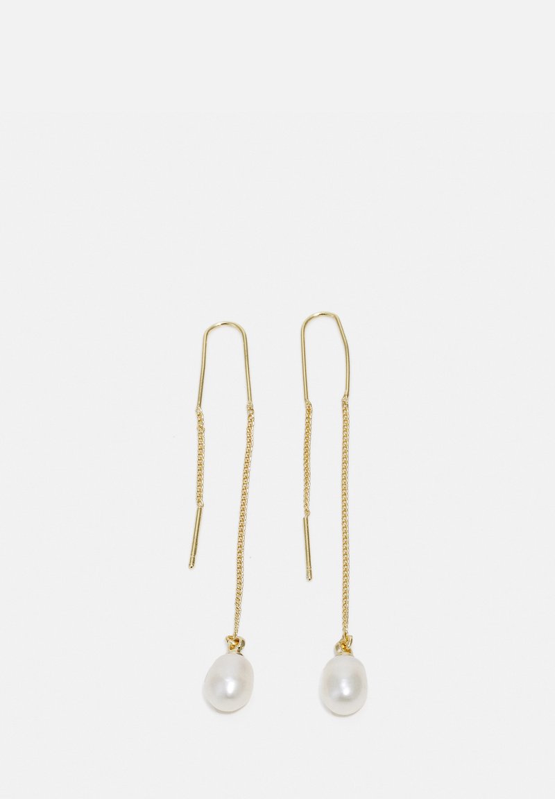 Boucles d'oreilles en métal doré avec de longs éléments en chaîne et deux pendentifs en perles blanches à l'extrémité. Les perles ont une forme ronde et lisse.