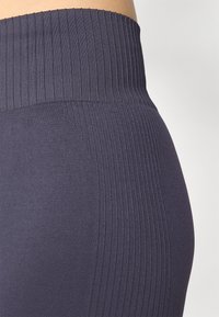 Navy leggings featuring a ribbed high waistband, smooth texture, and fitted design, with a clean line and minimal detailing.