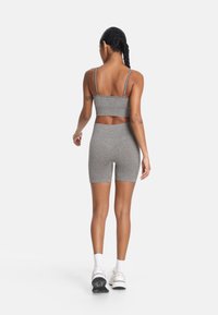 Sivý športový set obsahujúci priliehavý crop top s tenkými ramienkami a zodpovedajúce vysoké šortky. Hladká textúra a elastický materiál.