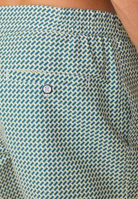 Bunte gemusterte Shorts in Blau, Gelb und Weiß. Mit einer Gesäßtasche mit Knopf und einem subtilen strukturierten Design.