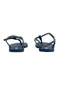 Chanclas negras con suelas texturizadas y tiras brillantes. Las tiras cuentan con un acento decorativo y brillante sobre un material suave.